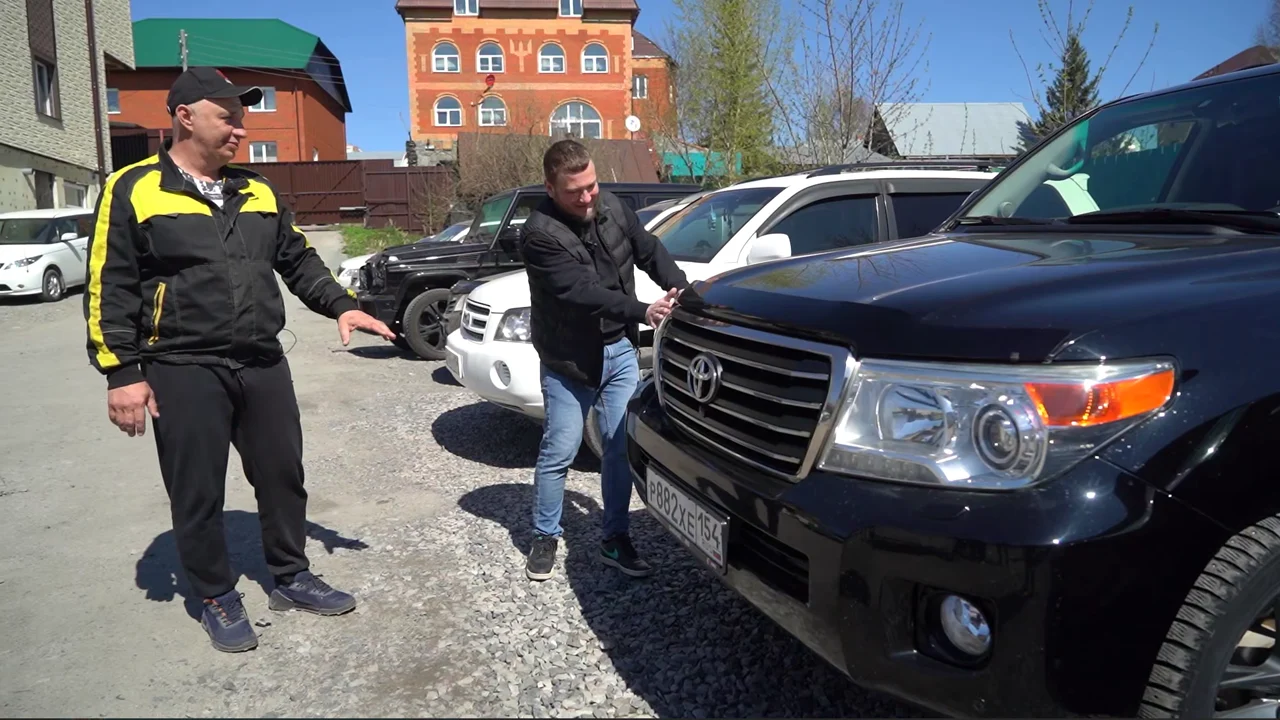 Николай Лончаков осматривает полученный Toyota Land Cruiser 200 рядом с ведущим Garage 54