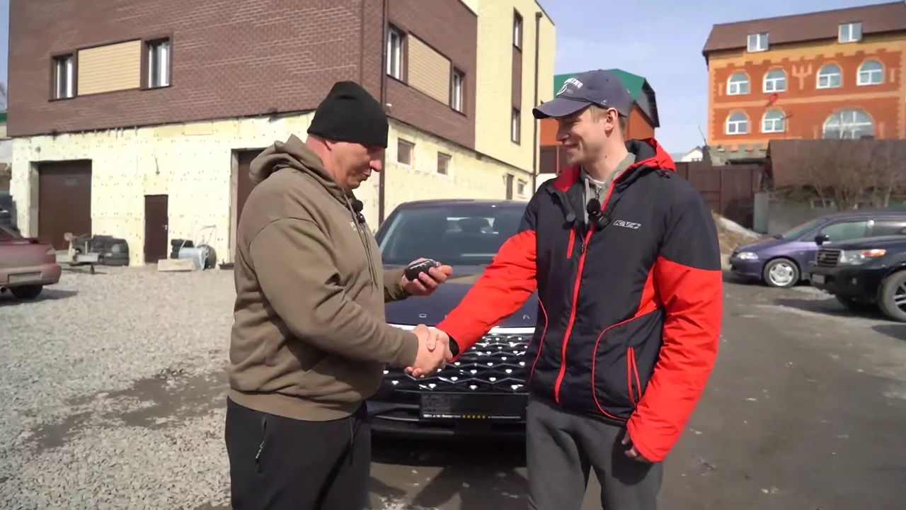 Ведущий Garage 54 пожимает руку Виктору Корягину с ключами от OMODA C5
